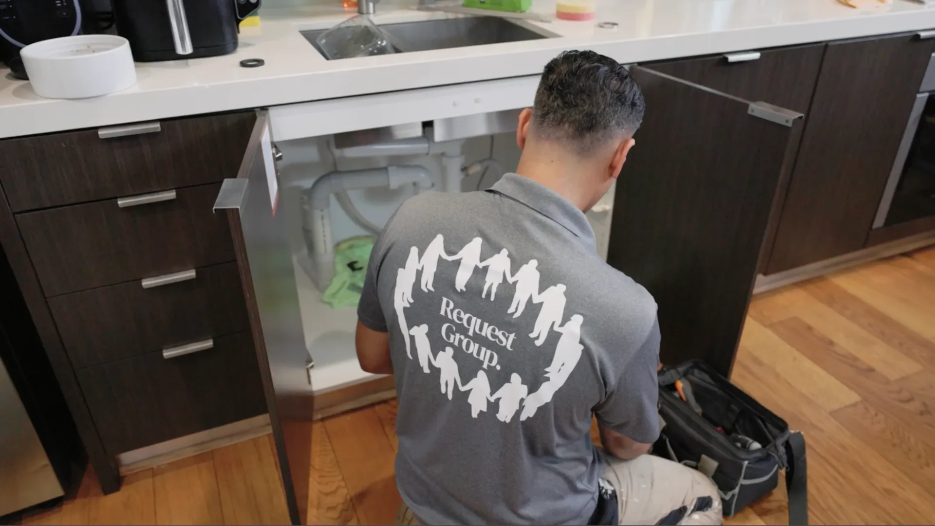 Request Group team member repairing kitchen appliance wearing branded uniform